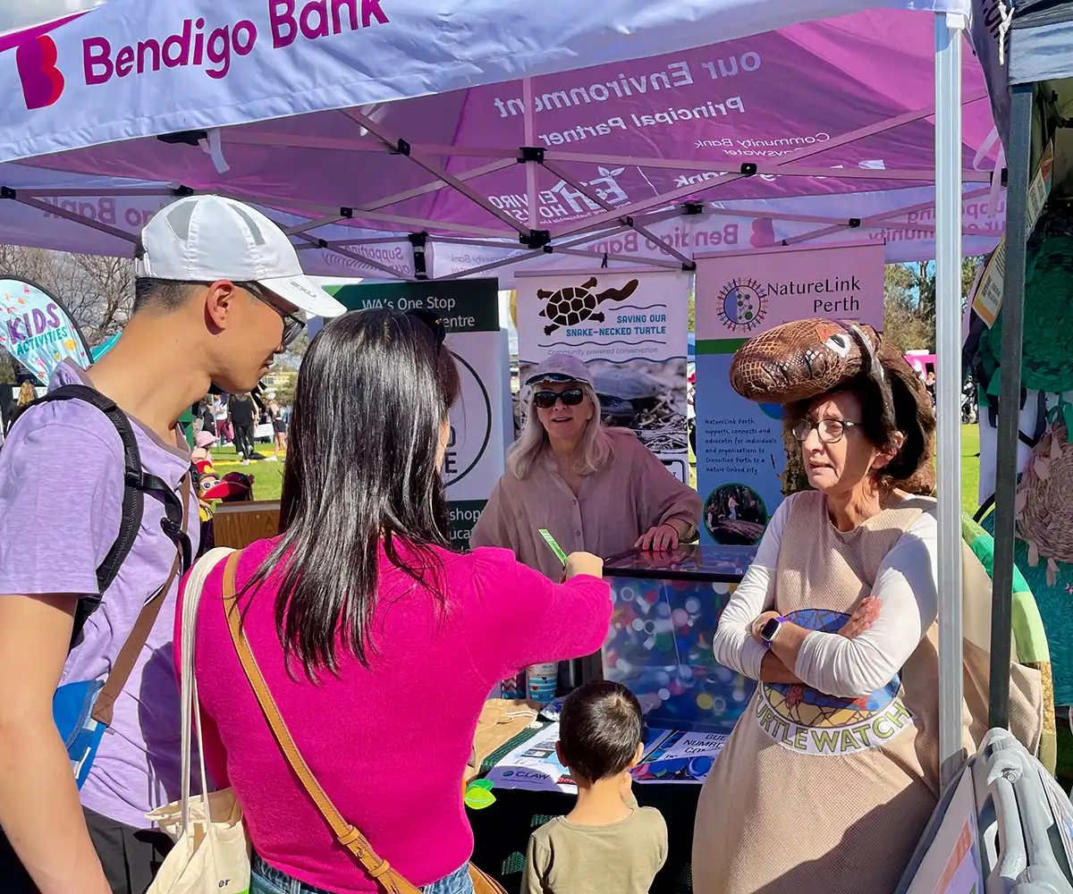 An information stall showing a volunteer in a turtle costume with a family stopping to learn more