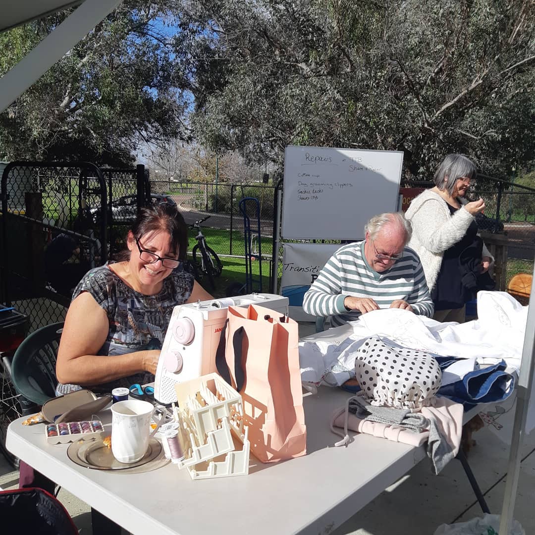 A volunteer mending clothing at a repair session